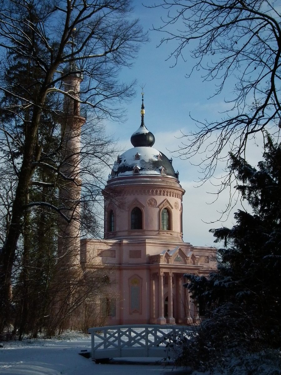 Die Rote Moschee im Schwetzinger Schlossgarten zwischen Bäumen und Gartenanlagen.