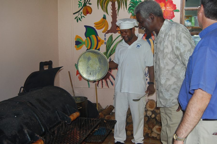 Zubereitung von Oil Down, einem traditionellen Eintopf aus Grenada, in einem großen Topf.