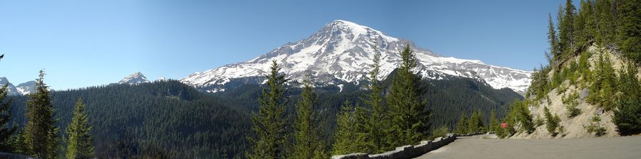 Panoramic view of Mount Rainier’s south face with snow and ice above the forested landscape.