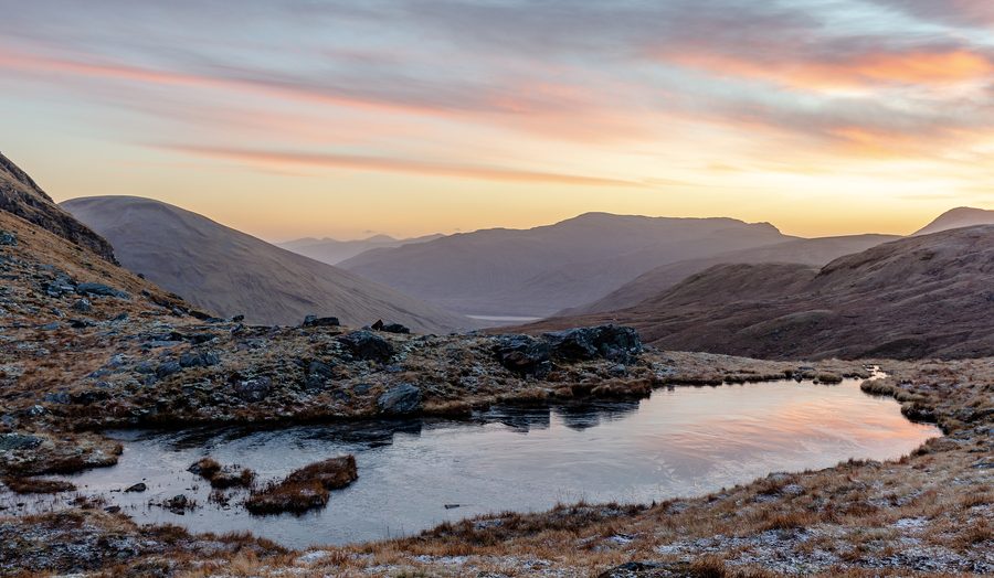 Piccolo lago tra le montagne nelle Highlands scozzesi all’alba