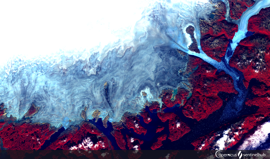 False-color satellite view of southern Greenland’s coastline and green valleys.