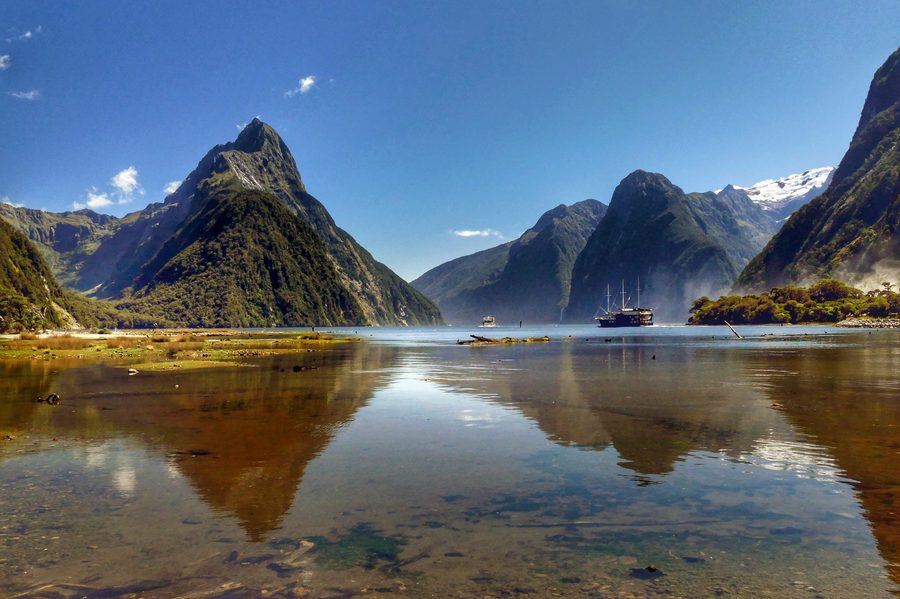 Milford Sound in Nuova Zelanda con ripide pareti rocciose modellate dai ghiacciai, cascate e acque scure del fiordo