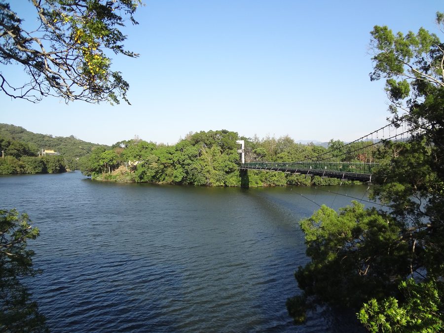 Hängebrücke über dem Mingde Reservoir in Touwu, umgeben von grünen Bergen