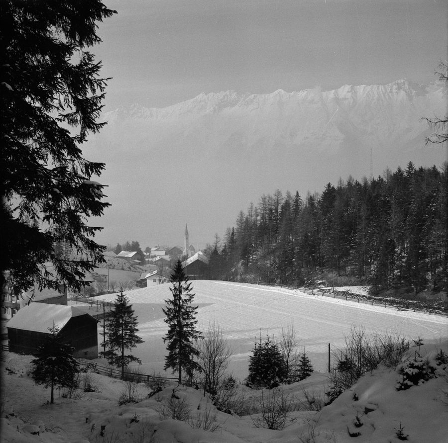 Aldrans in Tirol als verschneites Dorf vor einer alpinen Berglandschaft