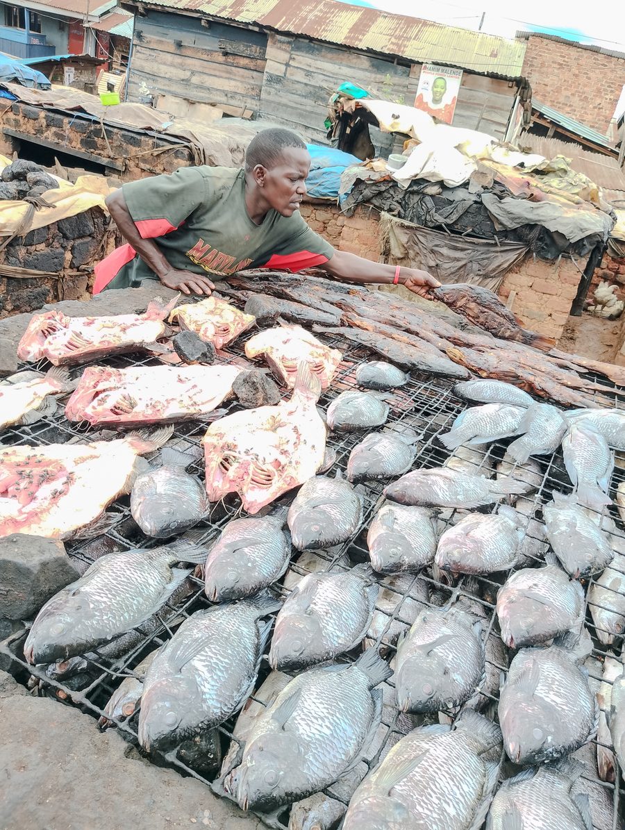 Venditrice di pesce con pesce tradizionalmente affumicato e fresco al Ggaba Landing Site in Uganda