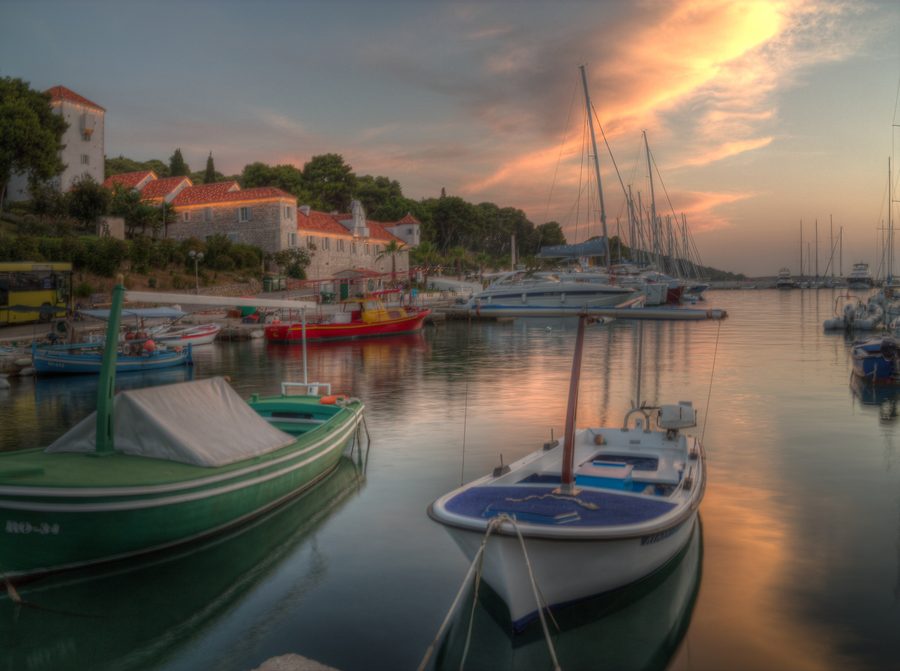 Hafen von Maslinica auf der Insel Šolta bei Sonnenuntergang mit Fischerboot und Küstenlandschaft