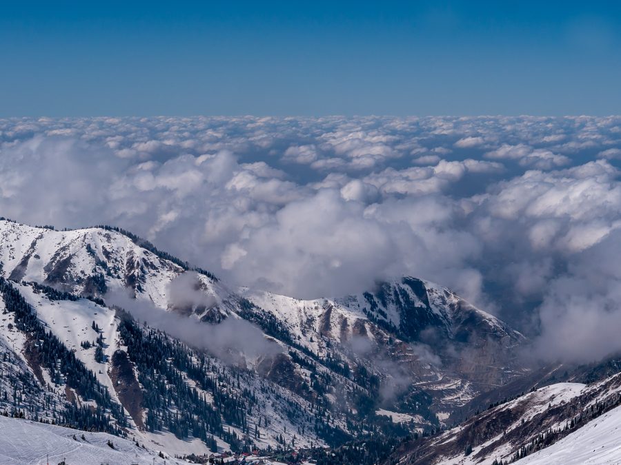 Almaty city centre seen below clouds from Shymbulak ski resort, with mountains in the foreground.