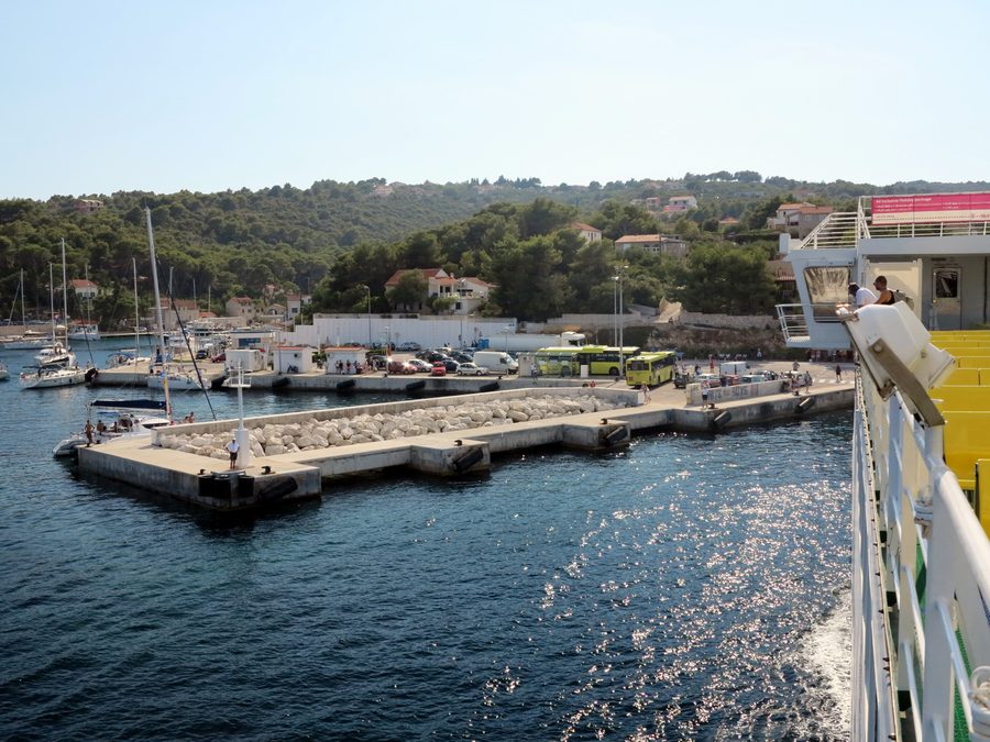 Rogač a Šolta con il molo dei traghetti e autobus gialli al porto