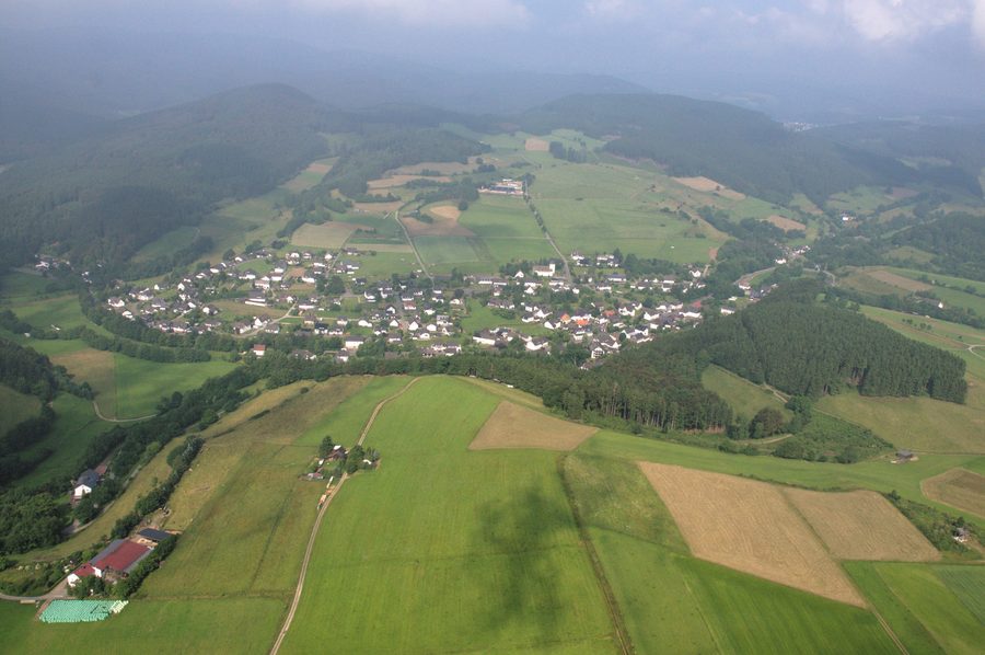 Luftaufnahme von Hallenberg-Liesen mit Offenland und bewaldeten Hängen im Hintergrund