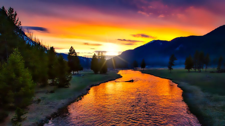 Tramonto sul Parco nazionale di Yellowstone con luce calda e nuvole sopra il paesaggio.