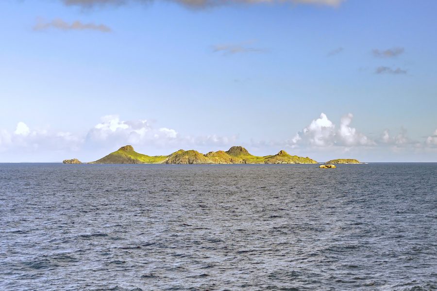Blick vom Meer auf die felsige, trocken bewachsene Île Fourchue vor Saint-Barthélemy.