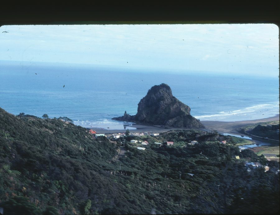 Spiaggia di Piha con sabbia nera, surf e promontori rocciosi.