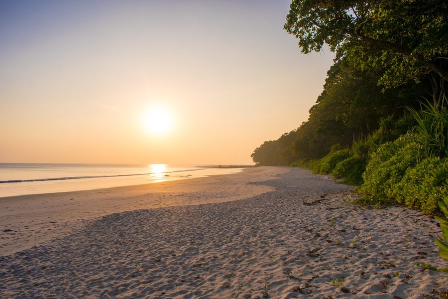 Sunrise over the Andaman Islands coastline with calm blue water.