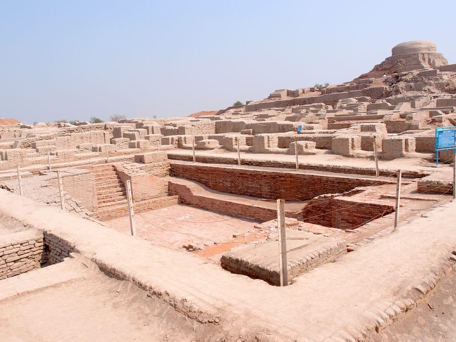 Ausgegrabene Ruinen von Mohenjo-Daro mit dem Great Bath im Vordergrund und einem erhöhten Ruinenhügel im Hintergrund